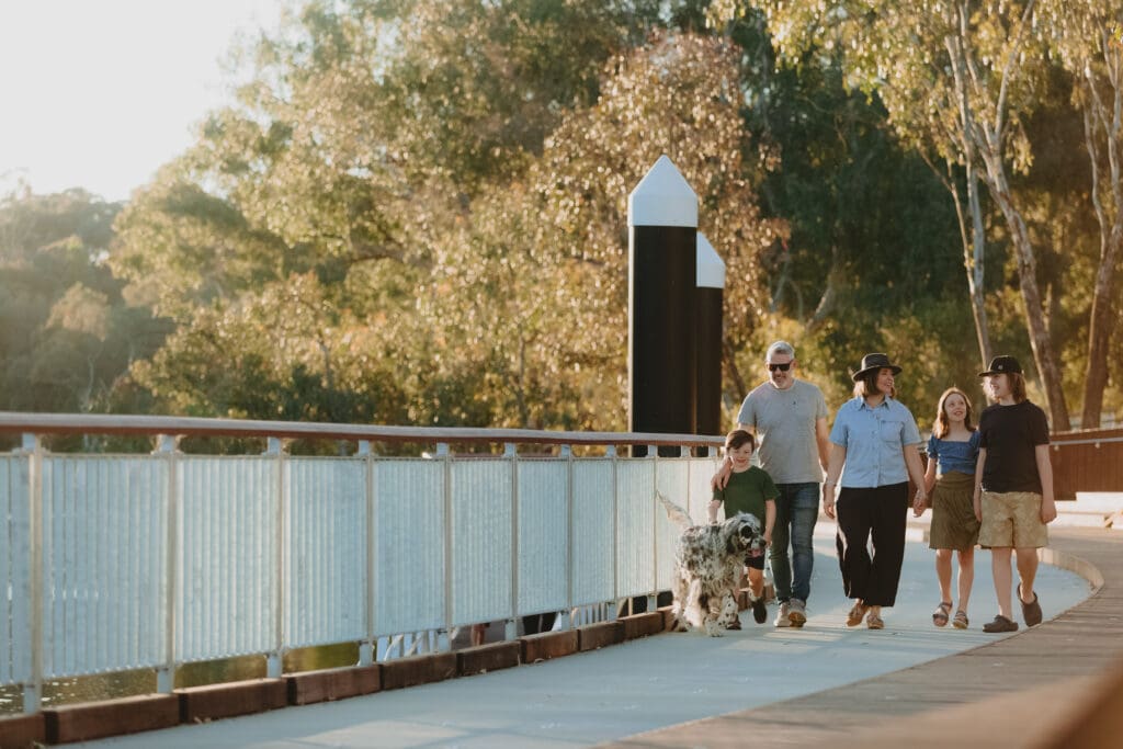 A family with a dog walk along the Murray river boardwalk