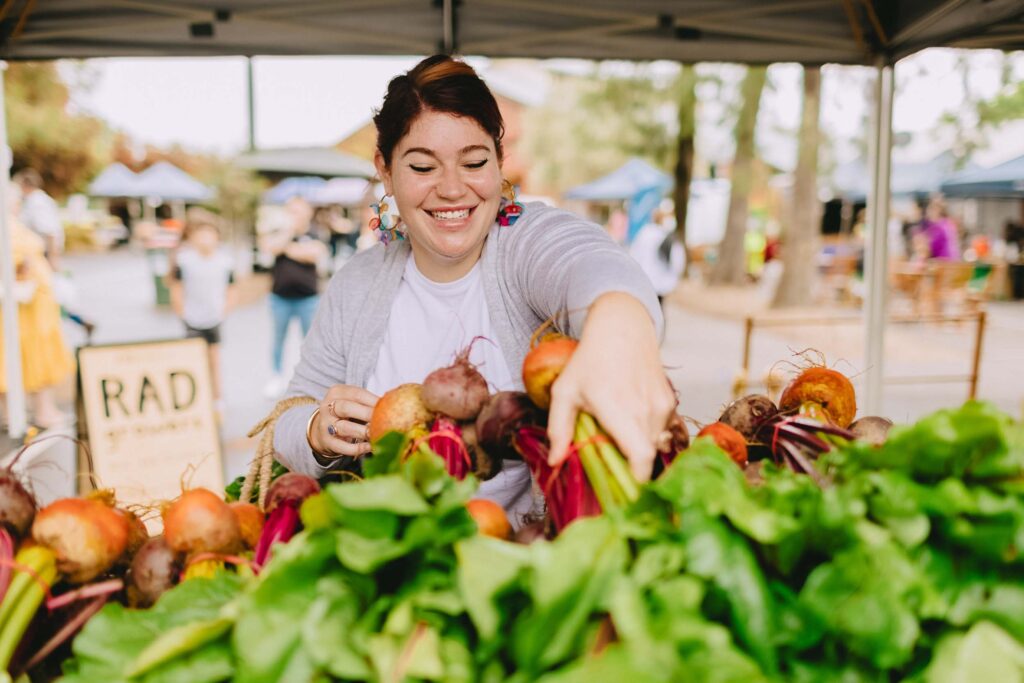Woman selects vegetables at farmers market stall