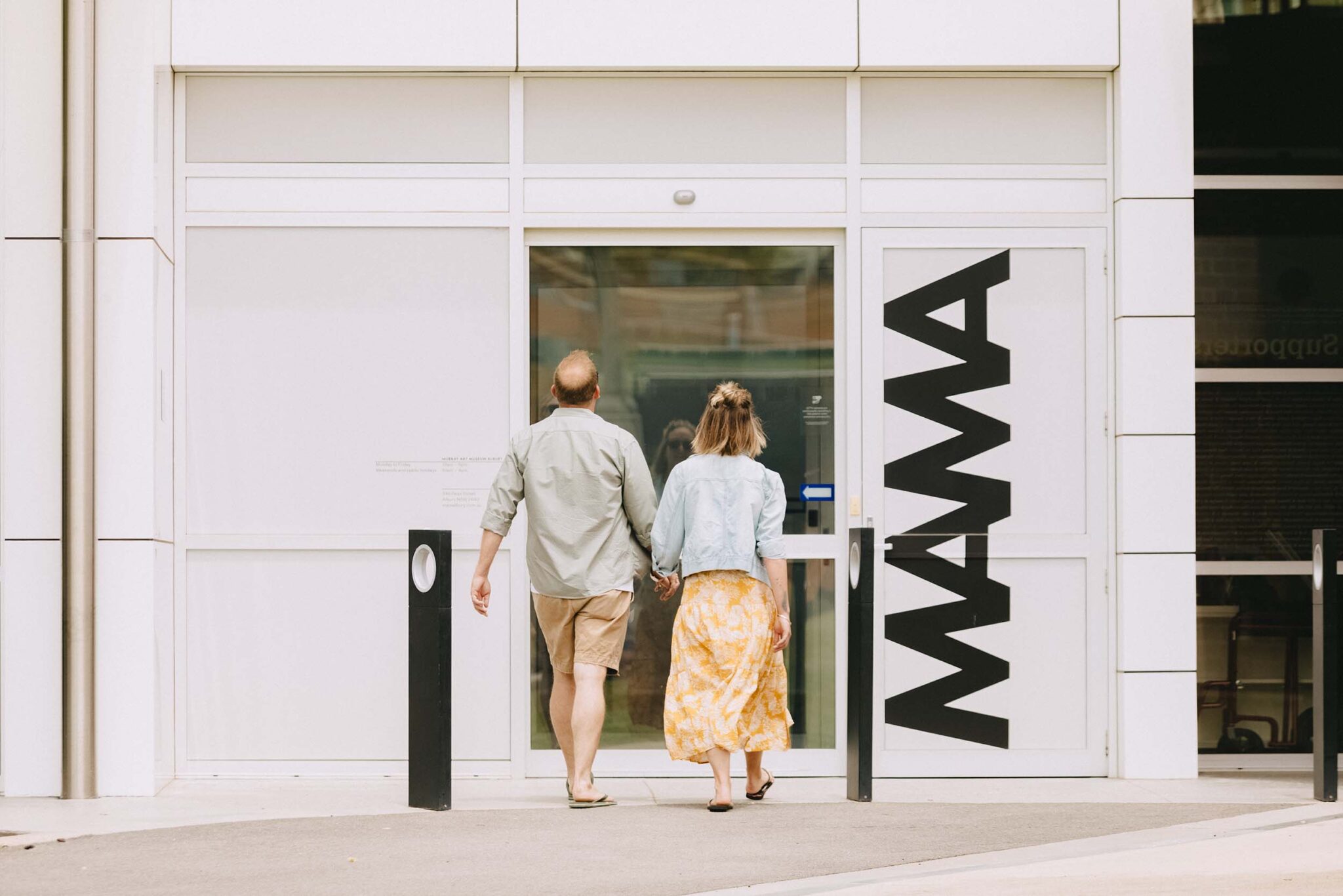 Man and woman holding hands walking towards door of museum