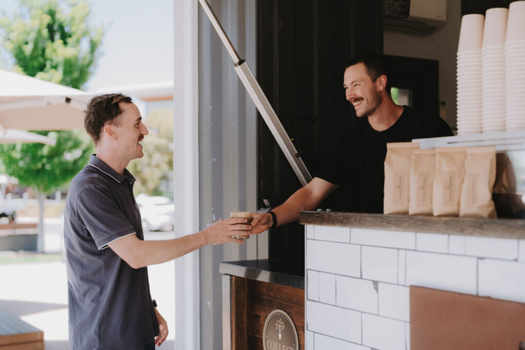 man reaching to get a coffee from the barista