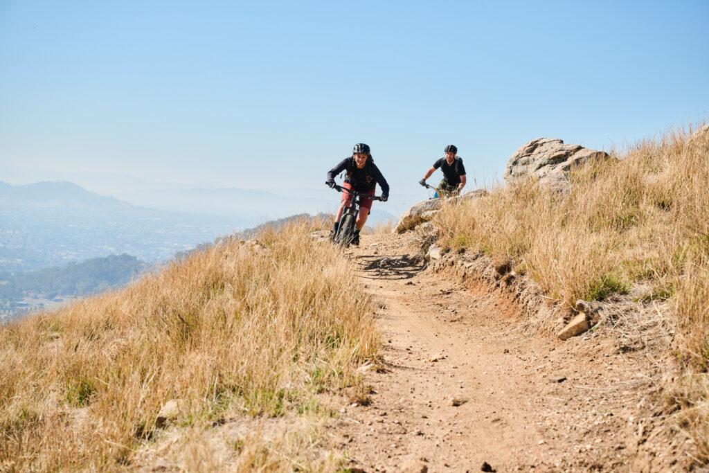 two people riding down a hill on mountain bikes