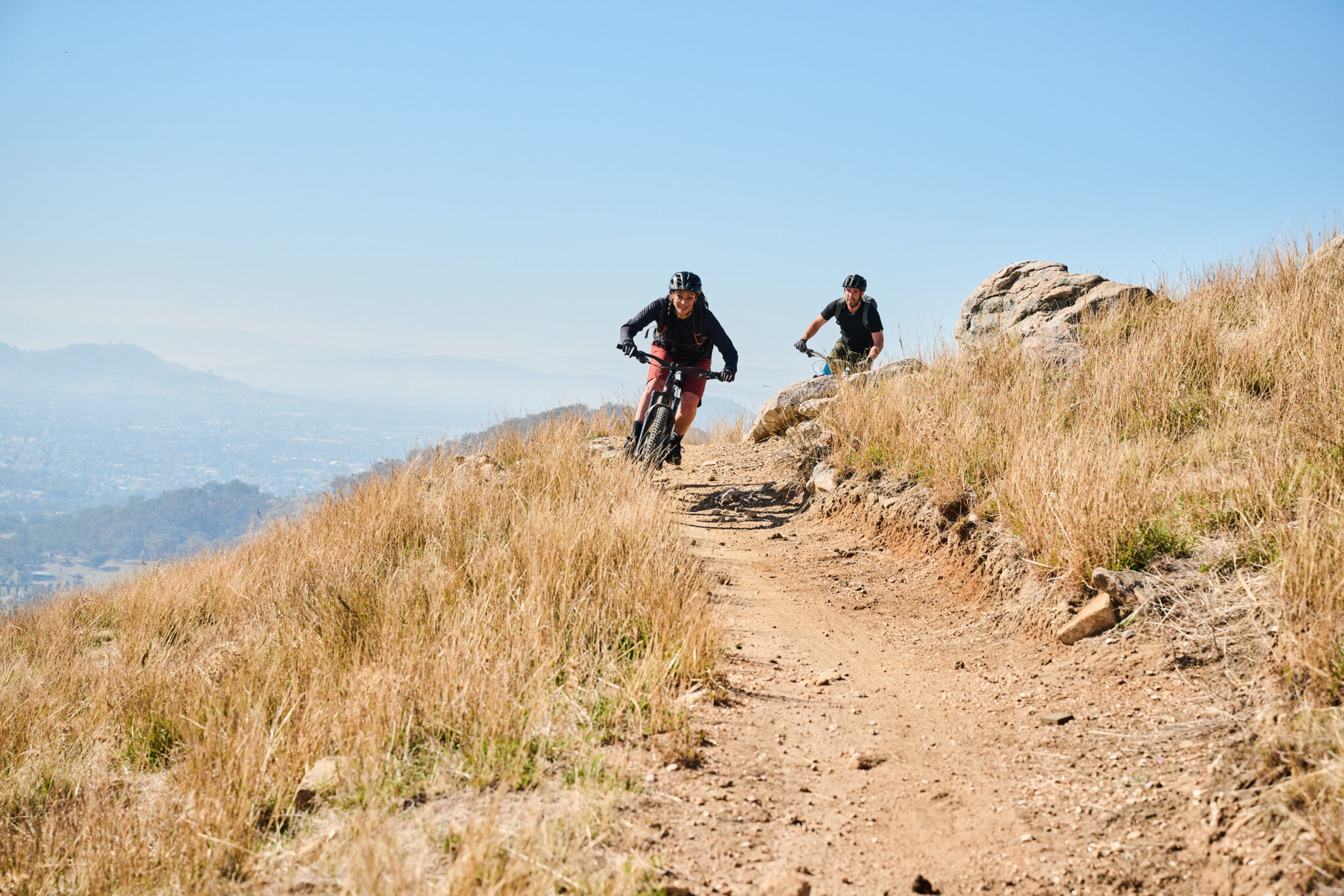 two people riding down a hill on mountain bikes