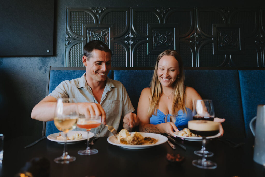 A man and a woman enjoying cocktails and food