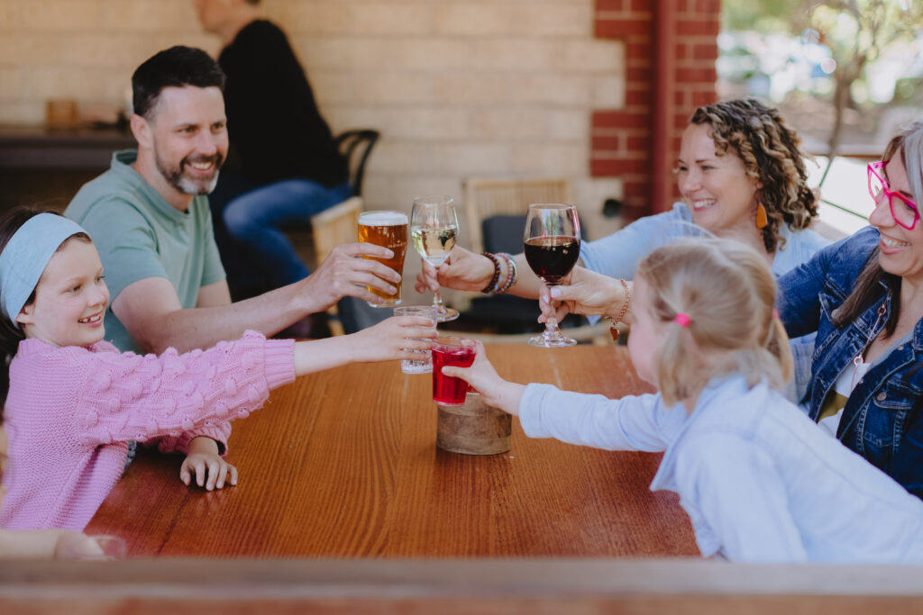 A family is sitting at a table lifting their glasses to cheers each other