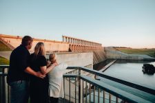 Family standing on viewing platform look at dam wall